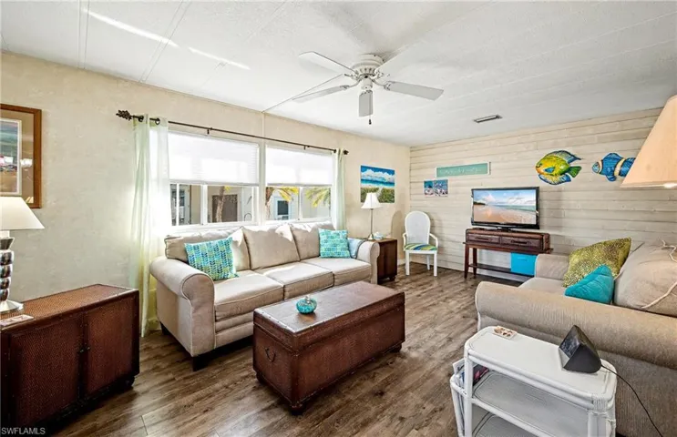 Living room featuring wood finished floors, a ceiling fan, and wooden walls