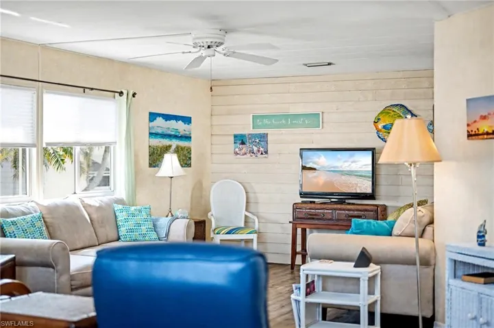 Living room with wood finished floors, ceiling fan, and wood walls