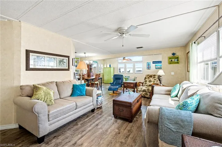 Living area with wood finished floors, healthy amount of natural light, and ceiling fan