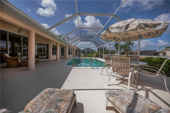 Screened-in outdoor living space with an in-ground swimming pool, expansive concrete patio, and direct access to interior rooms via multiple glass doors