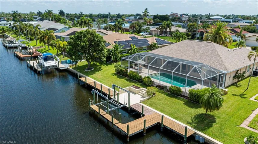 Waterfront property featuring a screened-in swimming pool, private boat dock, and lush green lawn