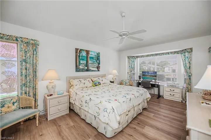 Bright bedroom featuring wood-finish flooring and a white ceiling fan