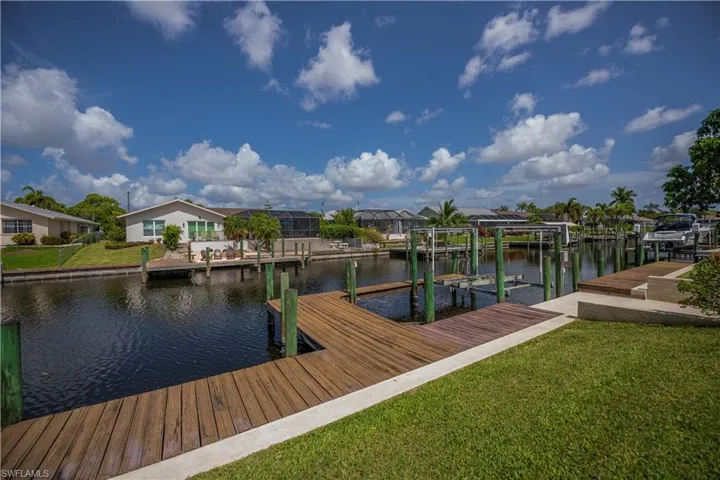 Waterfront property featuring a wood-finish dock, concrete seawall, and boat lift