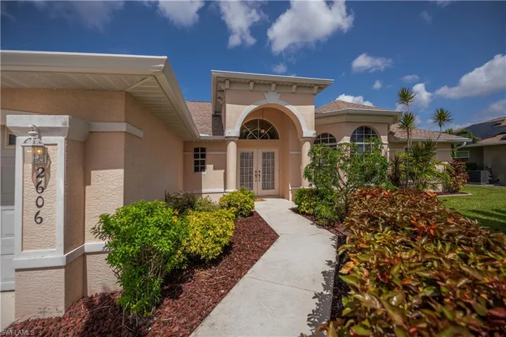 Stucco exterior with arched entry, double front doors, and a bay window
