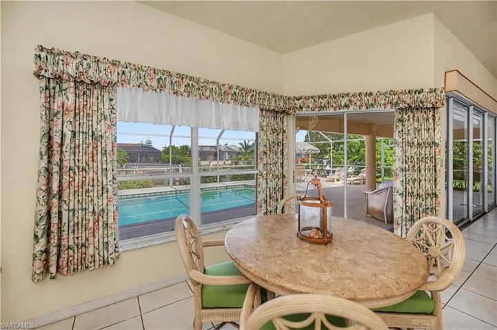 Dining area featuring a tiled floor and a large window overlooking a swimming pool
