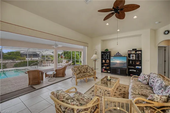Bright open-concept living area featuring large format tile flooring and a ceiling fan with recessed lighting
