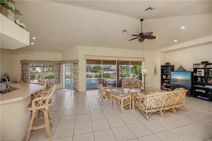 Spacious living area featuring large format tile flooring and vaulted ceilings