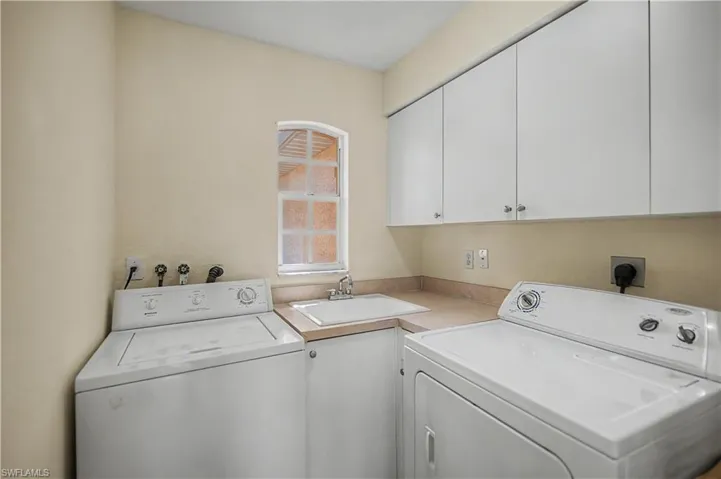 Dedicated laundry area featuring a utility sink, countertop space, and upper cabinetry