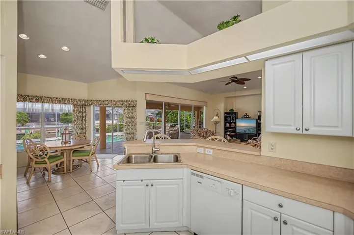 Kitchen featuring white cabinetry, light-toned countertops, and a double-basin stainless steel sink