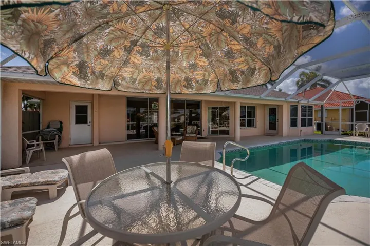 Screened-in pool deck featuring a clear blue swimming pool with a handrail, a concrete patio, and a covered lanai