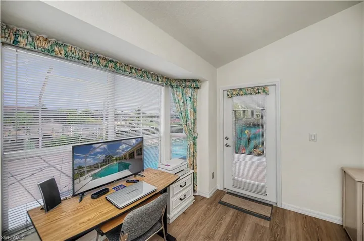 Interior space featuring wood-finish flooring, vaulted ceiling, and an exterior door with decorative glass inserts