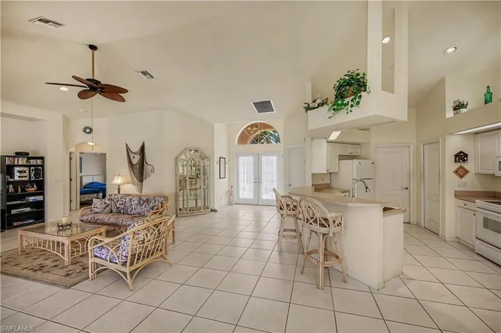 Spacious living area featuring tile flooring, vaulted ceilings, and a ceiling fan
