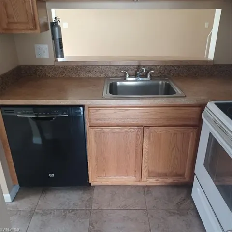 Kitchen with dishwasher, range, and light tile patterned flooring