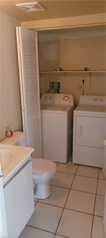 Bathroom featuring washing machine and clothes dryer, vanity, and tile patterned flooring