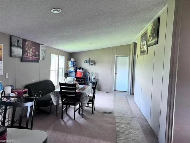 Dining area featuring carpet floors, a textured ceiling, and a decorative wall