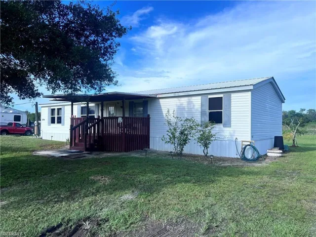 Manufactured / mobile home with a front yard, a metal roof, and a porch