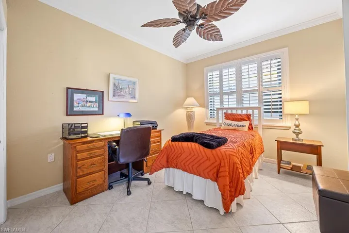 Bedroom featuring ornamental molding, light tile patterned flooring, a ceiling fan, and a desk