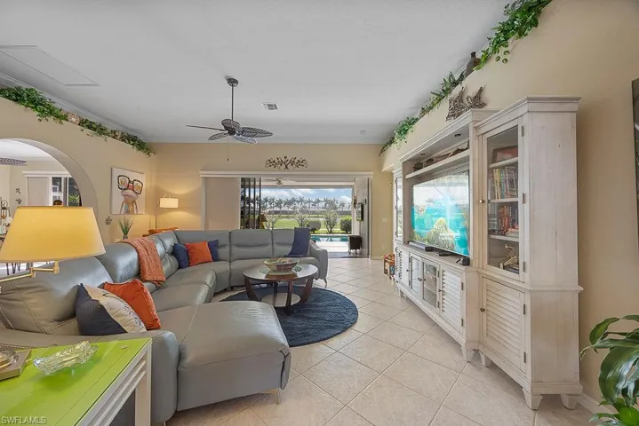 Living room with a ceiling fan, light tile patterned floors, and crown molding