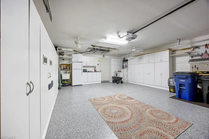 Garage featuring freestanding refrigerator, ceiling fan, and a garage door opener