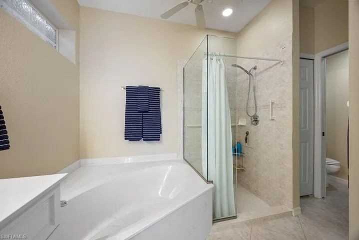 Full bathroom with a garden tub, a shower stall, a ceiling fan, vanity, and tile patterned flooring