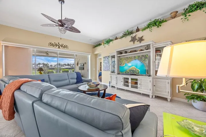 Living room with light tile patterned floors, ceiling fan, and ornamental molding