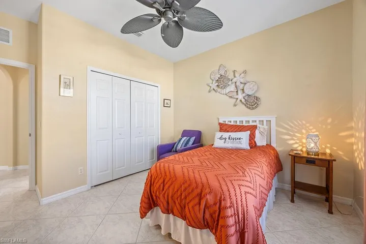 Bedroom with light tile patterned floors, a closet, and a ceiling fan
