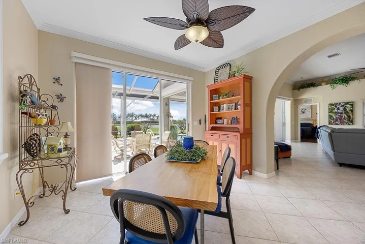 Dining room featuring arched walkways, a ceiling fan, light tile patterned floors, and ornamental molding