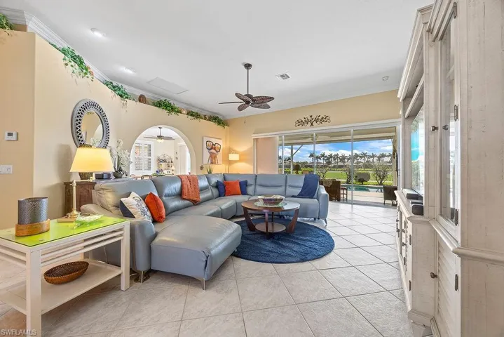 Living room with ceiling fan, light tile patterned floors, and crown molding