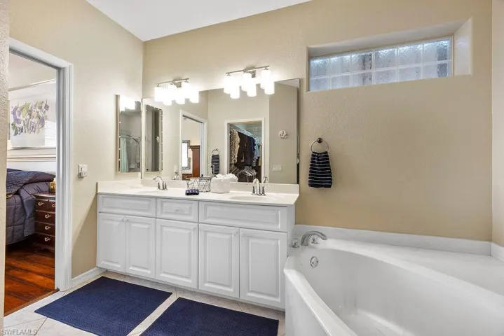 Ensuite bathroom featuring double vanity, tile patterned flooring, and a garden tub