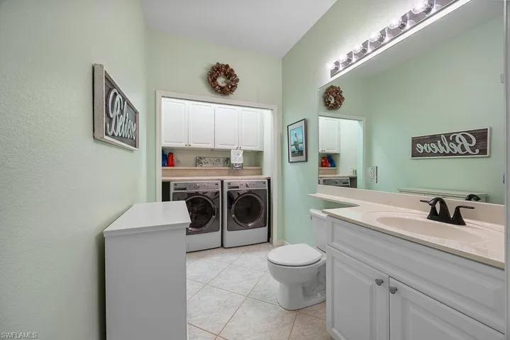 Washroom with washing machine and dryer, cabinet space, and light tile patterned floors