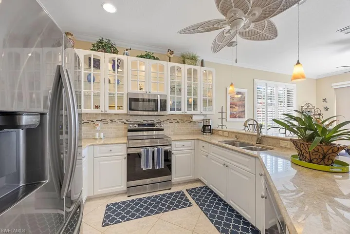 Kitchen with stainless steel appliances, ornamental molding, backsplash, ceiling fan, and hanging light fixtures