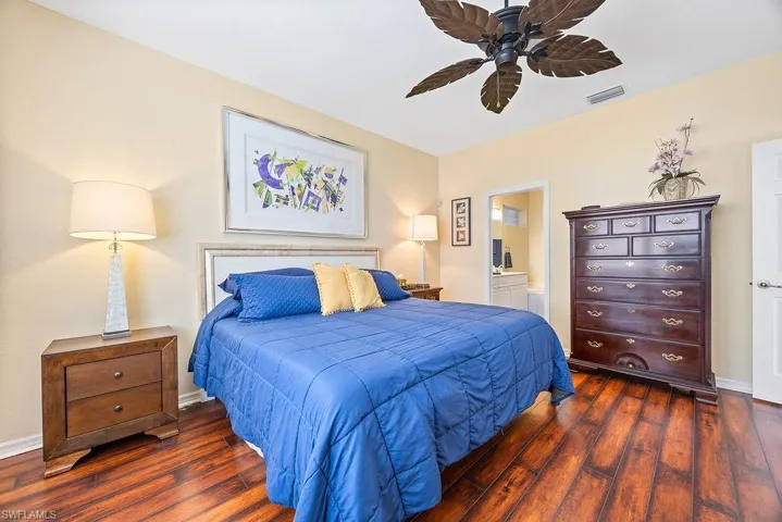 Bedroom with dark wood-type flooring, ensuite bathroom, and ceiling fan