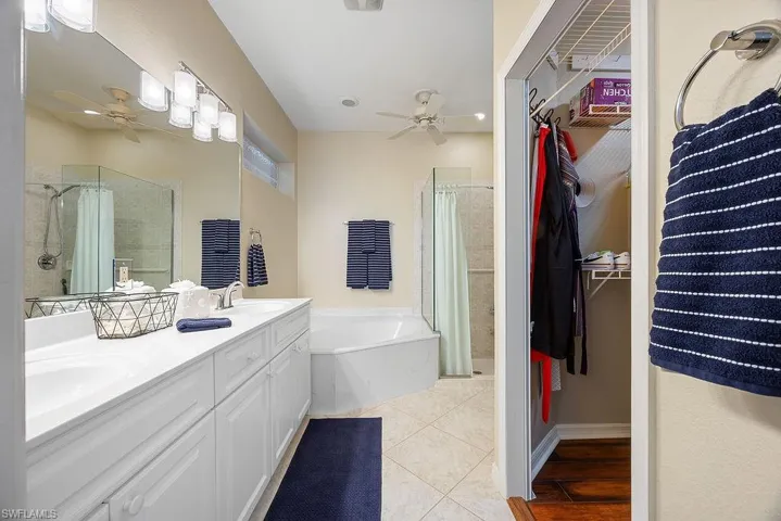 Bathroom with ceiling fan, a stall shower, a garden tub, and double vanity