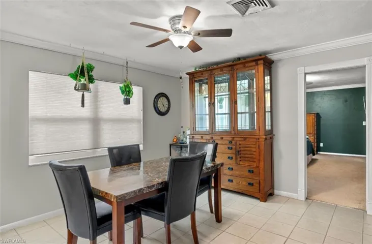 Tiled dining room featuring crown molding and ceiling fan
