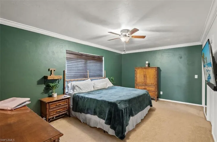 Carpeted bedroom featuring ornamental molding and ceiling fan