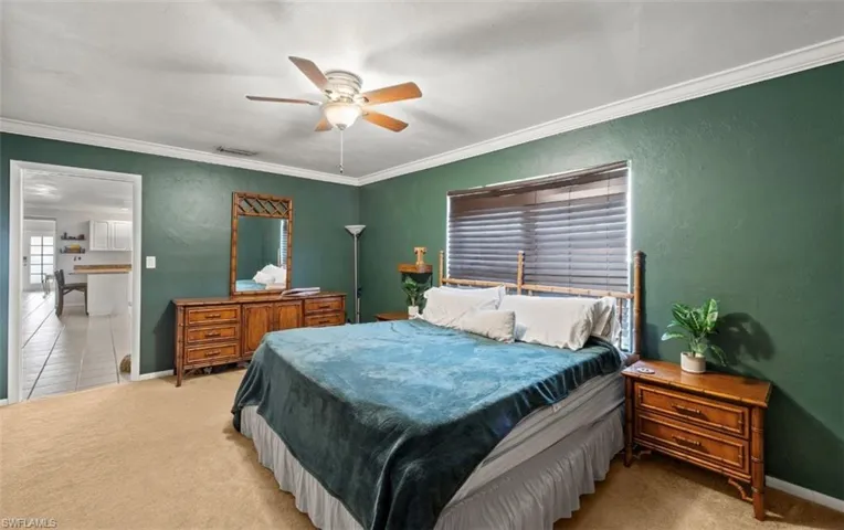 Carpeted bedroom with ceiling fan and crown molding