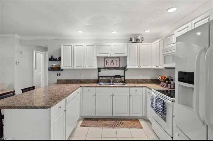 Kitchen featuring white cabinetry, white appliances, light tile patterned floors, and kitchen peninsula