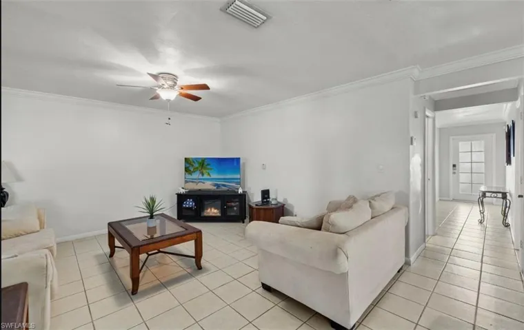 Tiled living room with ceiling fan and crown molding