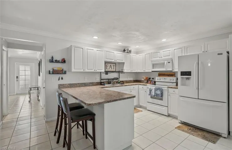 Kitchen featuring white cabinets, white appliances, light tile patterned floors, and kitchen peninsula