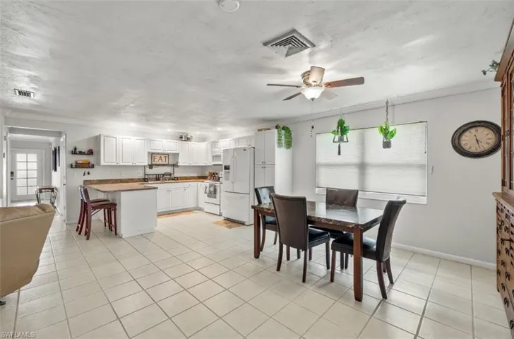 Dining room featuring crown molding, sink, light tile patterned floors, and ceiling fan