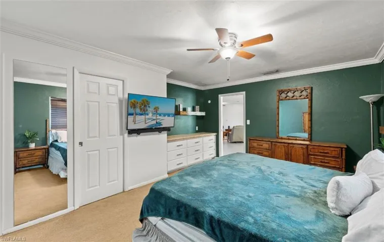 Carpeted bedroom featuring ornamental molding and ceiling fan