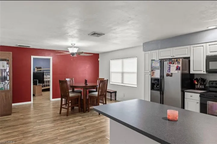 Kitchen featuring black appliances, wood-type flooring, ceiling fan, and white cabinets