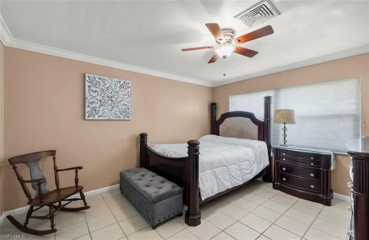 Bedroom featuring crown molding, light tile patterned floors, and ceiling fan