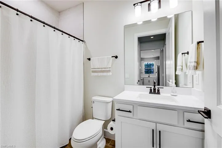Bathroom featuring vanity, toilet, and curtained shower