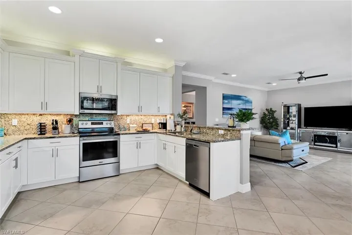 Kitchen with appliances with stainless steel finishes, stone counters, tasteful backsplash, and kitchen peninsula