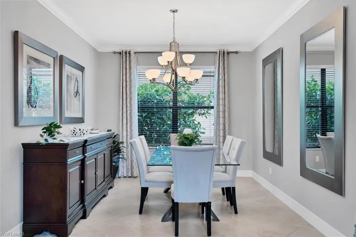 Tiled dining space featuring an inviting chandelier and crown molding