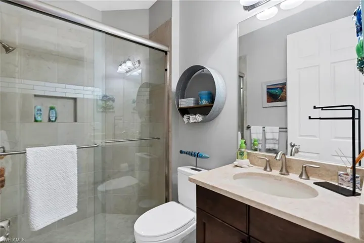 Bathroom featuring vanity, toilet, and a shower with door