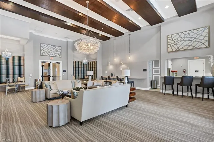 Living room with light carpet, beamed ceiling, a notable chandelier, a towering ceiling, and ornamental molding