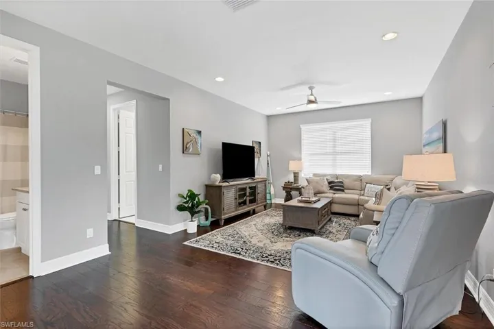 Living room with ceiling fan and dark wood-type flooring