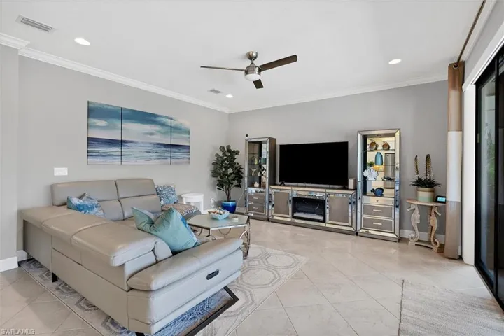 Living room with ceiling fan, light tile floors, and ornamental molding